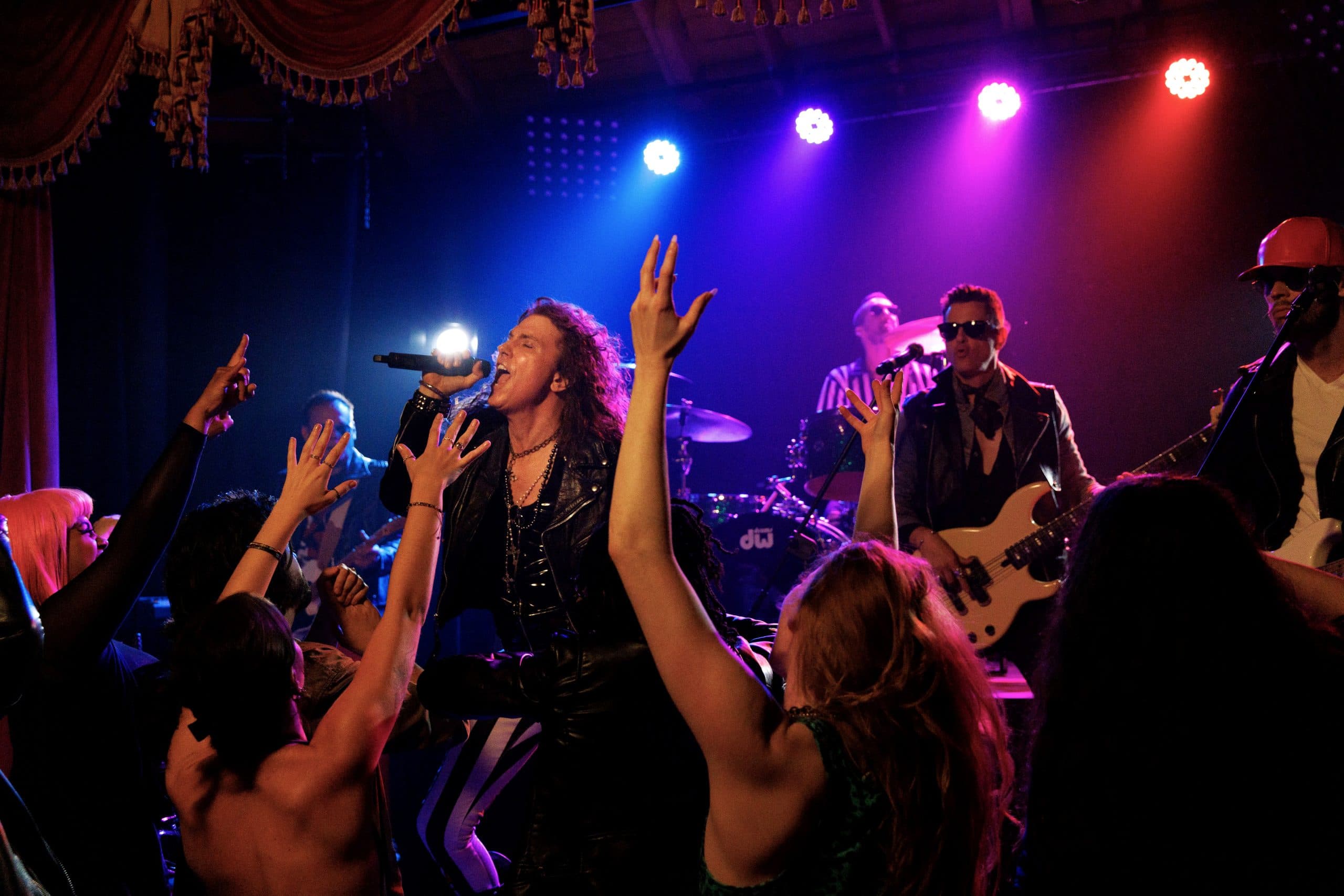 The band playing to a crowd under blue and purple stage light