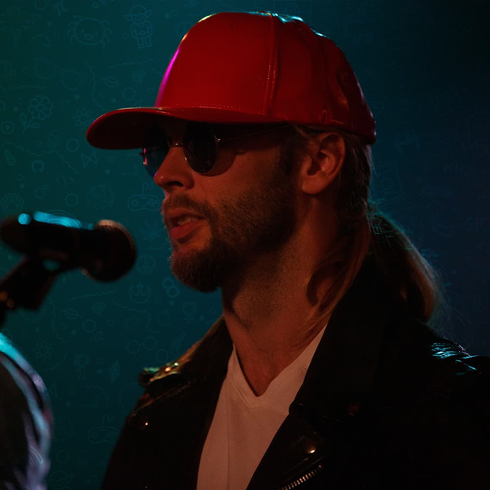 Jake Faun in a red cap and sunglasses beside a microphone