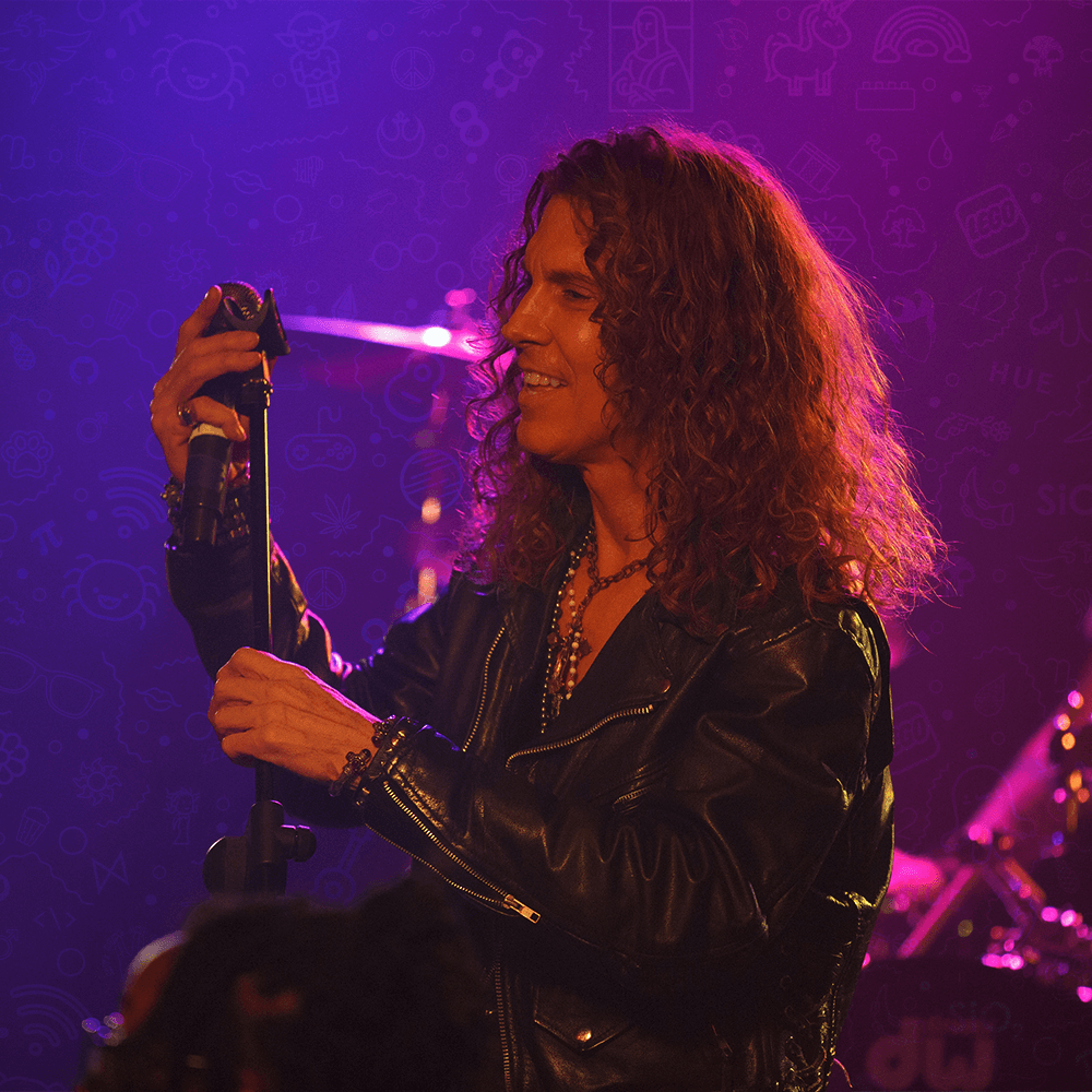 Keith St. John singing at a microphone under purple stage light