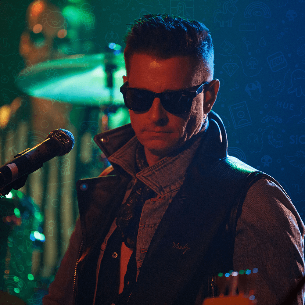 Victor Broden in sunglasses and a leather vest under green light